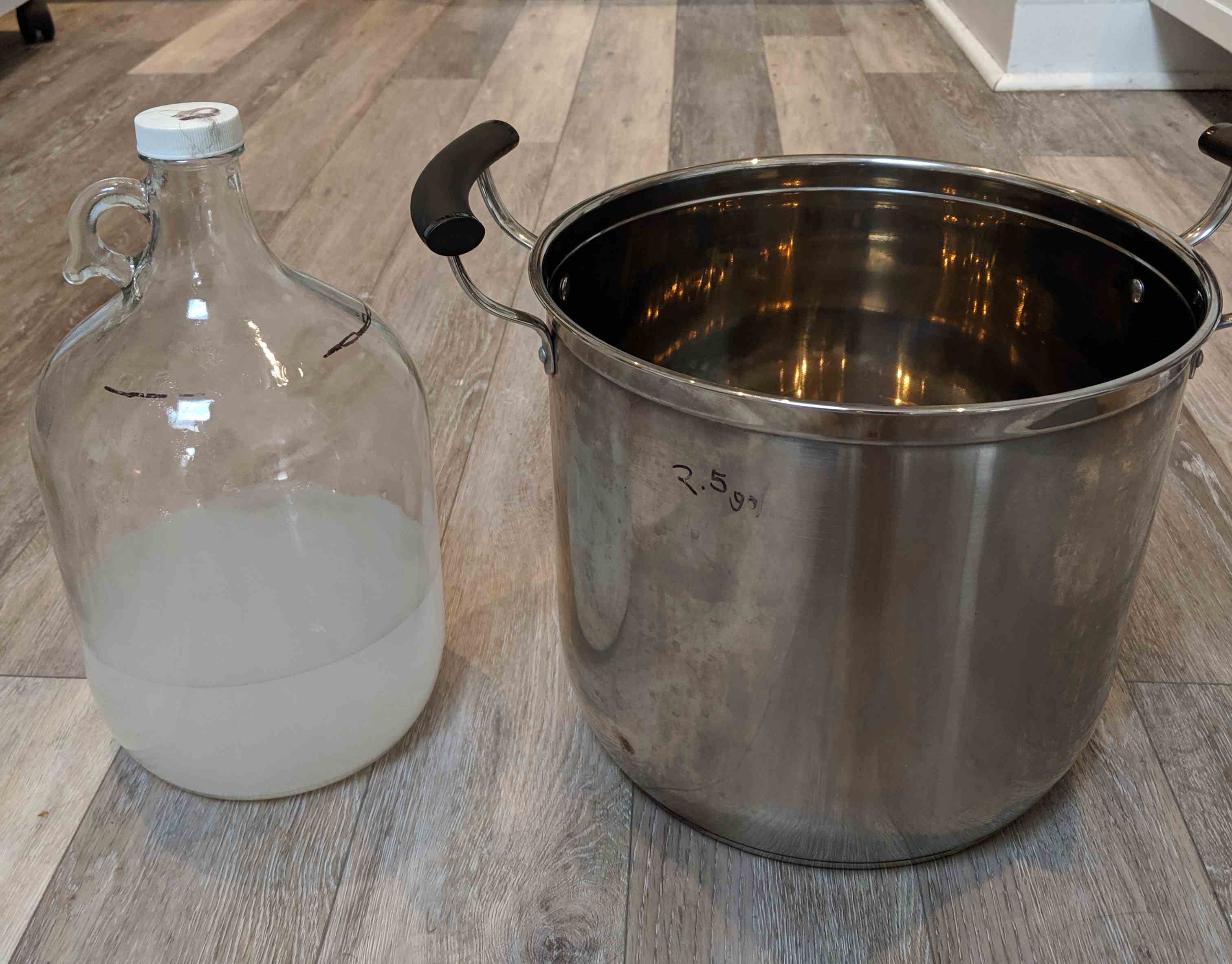 Left, a glass carboy filled with sanitizer. Right, an empty stainless steel stockpot